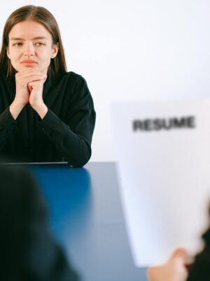 A woman in a job interview facing two employers with a focus on her resume.